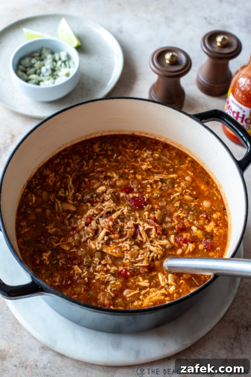 A large pot of buffalo chicken chili simmering on the stove, showing its rich texture