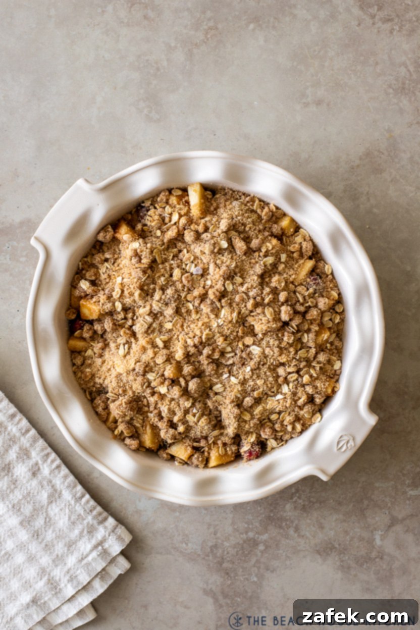 Spiced Apple Cranberry Crisp 9 Overhead photo of an unbaked apple cranberry crisp with topping spread evenly over the fruit