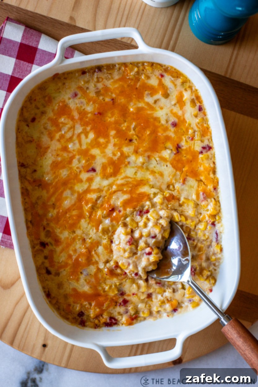 Up close overhead photo of a dish of pimento cheese creamy corn, highlighting the melted cheese and visible pimentos.